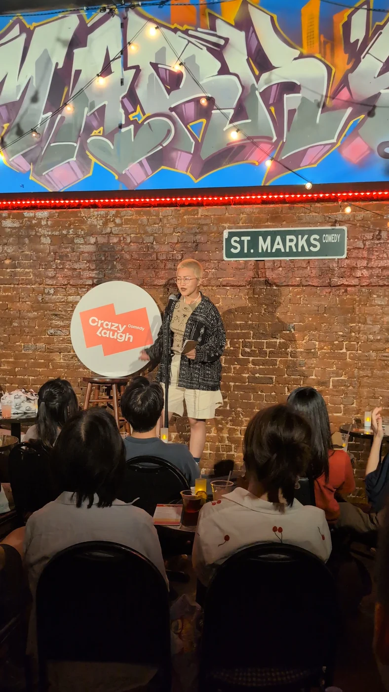 Raw ABEI performing beside the CrazyLaugh sign in front of an audience