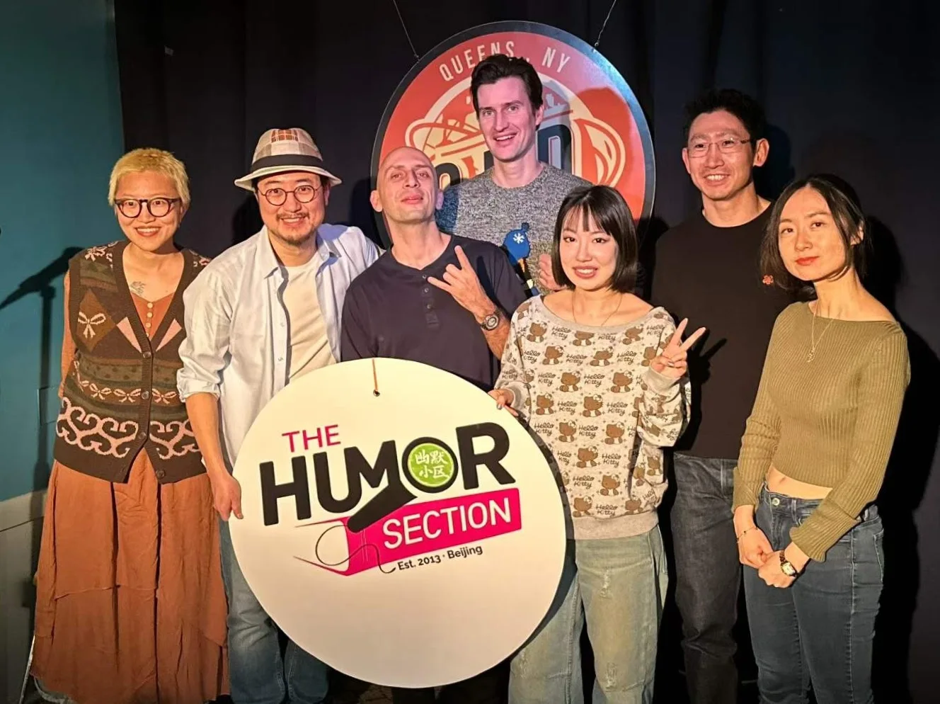 Raw ABEI with fellow performers holding The Humor Section sign