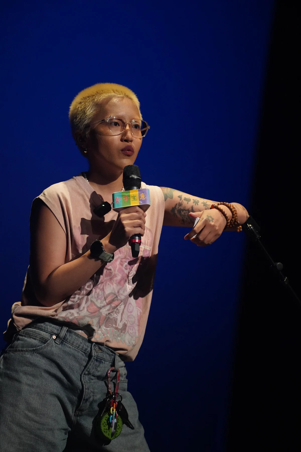 活人阿北 performing stand-up with a microphone and an expressive hand gesture on a blue-lit stage