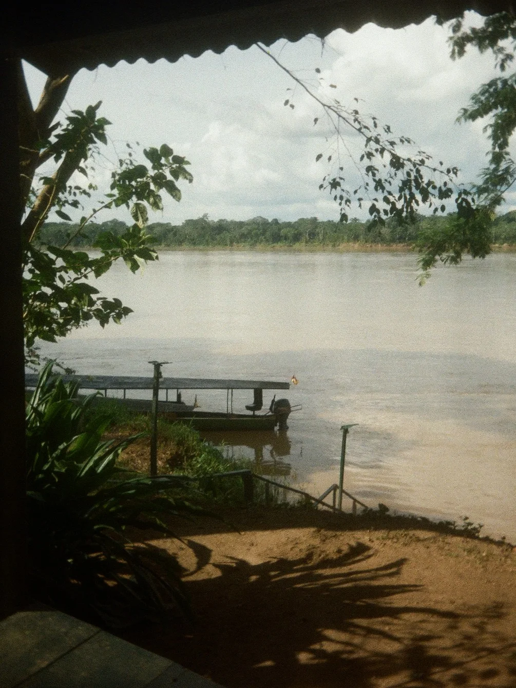 Film photograph of a broad river seen from a shaded bank