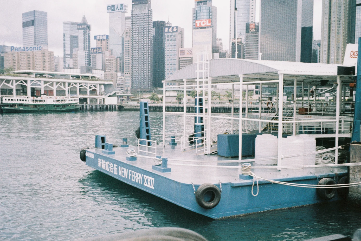 Film photograph of a city waterfront with modern buildings and a ferry